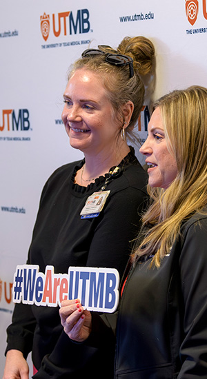 Logo Launch Employees Photo Booth Two UTM employees holding up the new UTMB slogan sign that reads #WeAreUTMB