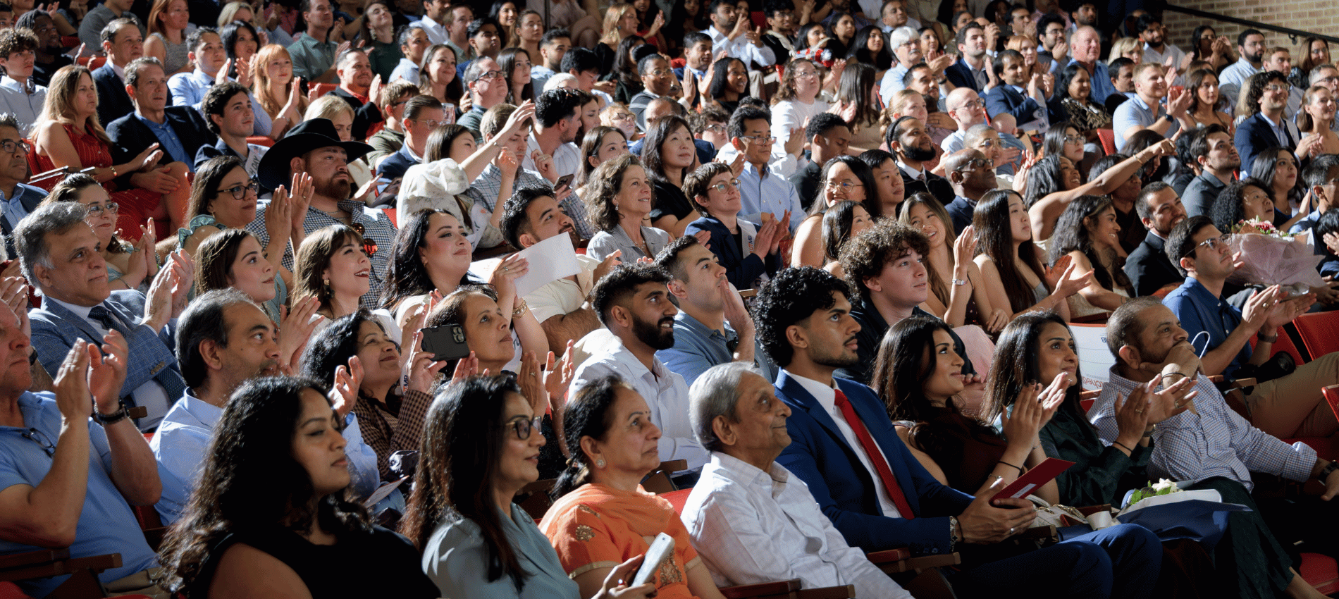 Medical students and their family and friends wait sit in a large auditorium waiting for Match Day envelopes