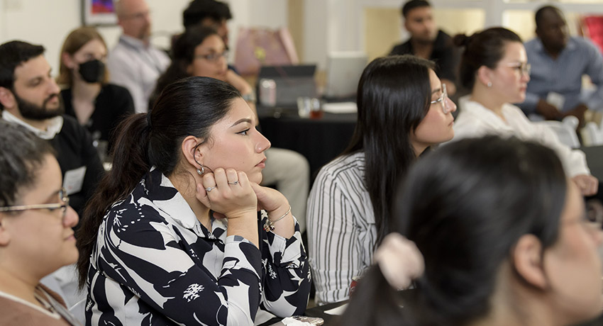 A group of six students look intently toward the front of the room, listening to speaker presentations during the 2025 Innovation Summer Camp.