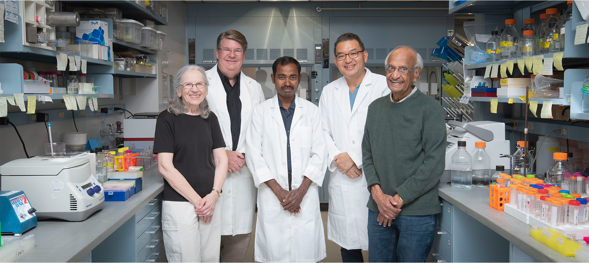 Five people standing in a lab setting at The University of Texas Medical Branch with three wearing white coats.