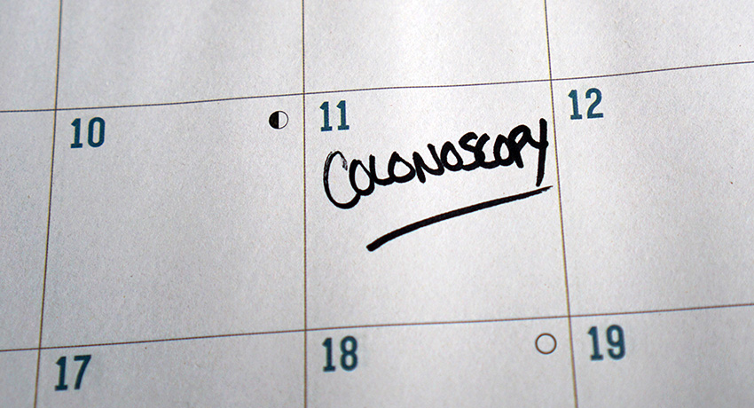 Close-up of a paper calendar with the word “Colonoscopy” handwritten and underlined on a scheduled date, emphasizing an upcoming medical screening appointment
