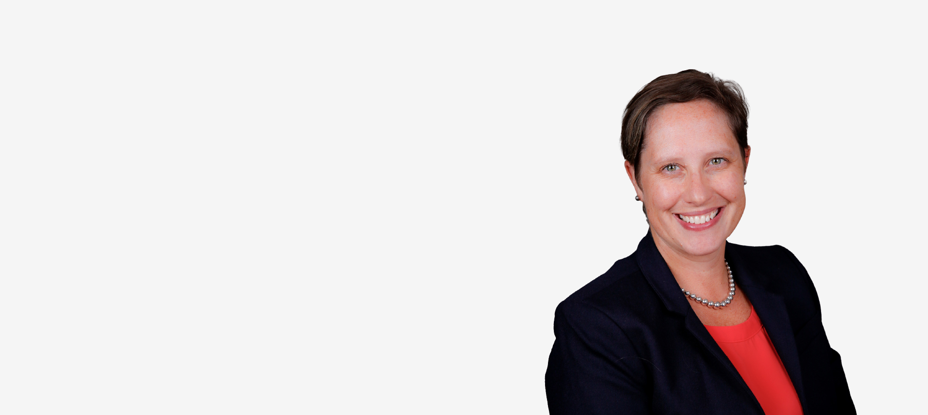 Dr. Cora Rabe, wearing a black jacket over a red shirt, smiles in a professional headshot.