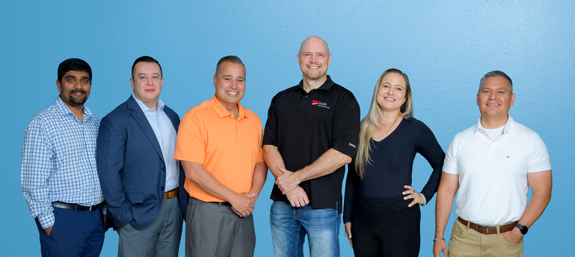 Five men and one woman in business and casual attire pose together in front of a blue background.