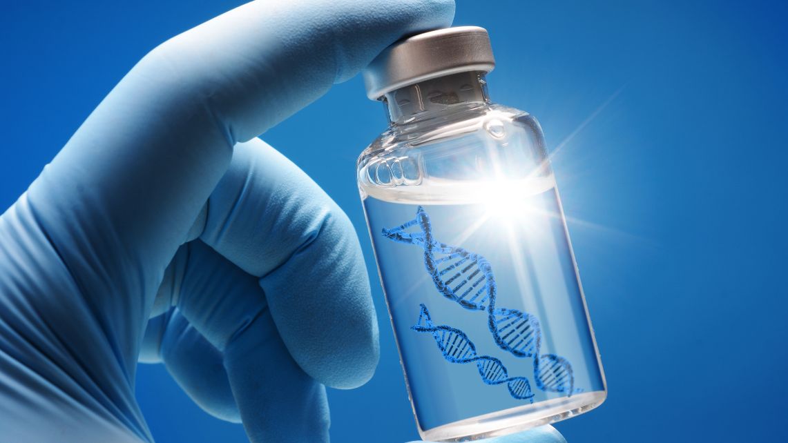 A gloved hand holds a vaccine vial with a stylized DNA strand graphic on the label against a blue background.