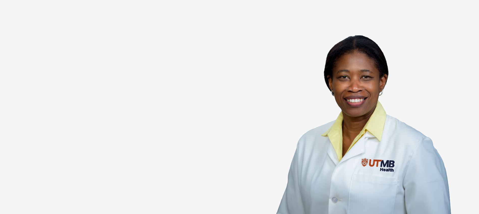 Studio headshot of a woman facing the camera, wearing a white lab coat with a UTMB Health logo over a light gray background.