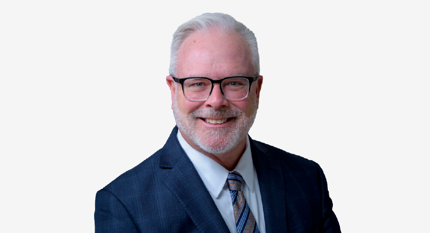 Dr. Jerry Mansfield appears in a headshot wearing a blue suit and tie.