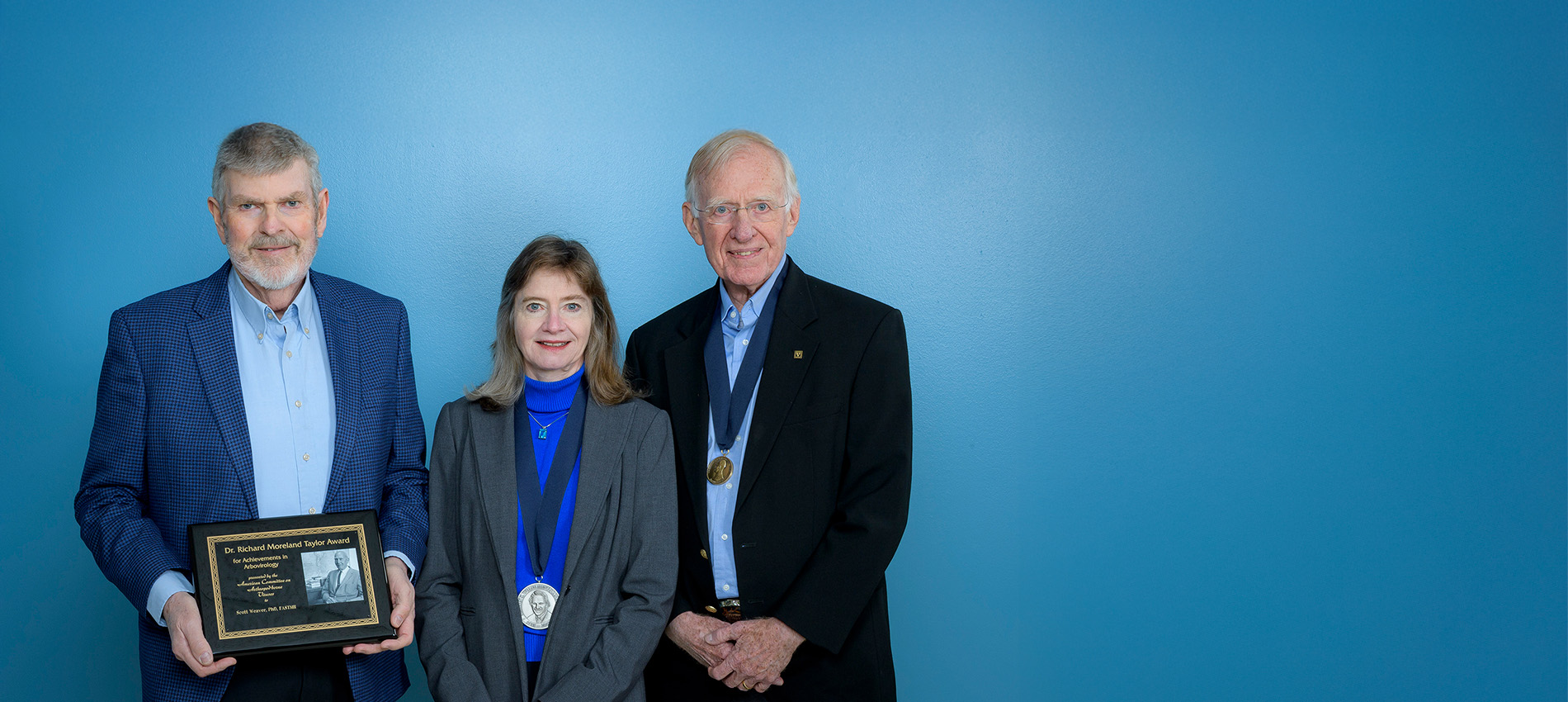 Three tropical medicine award winners display their plaques and medals.