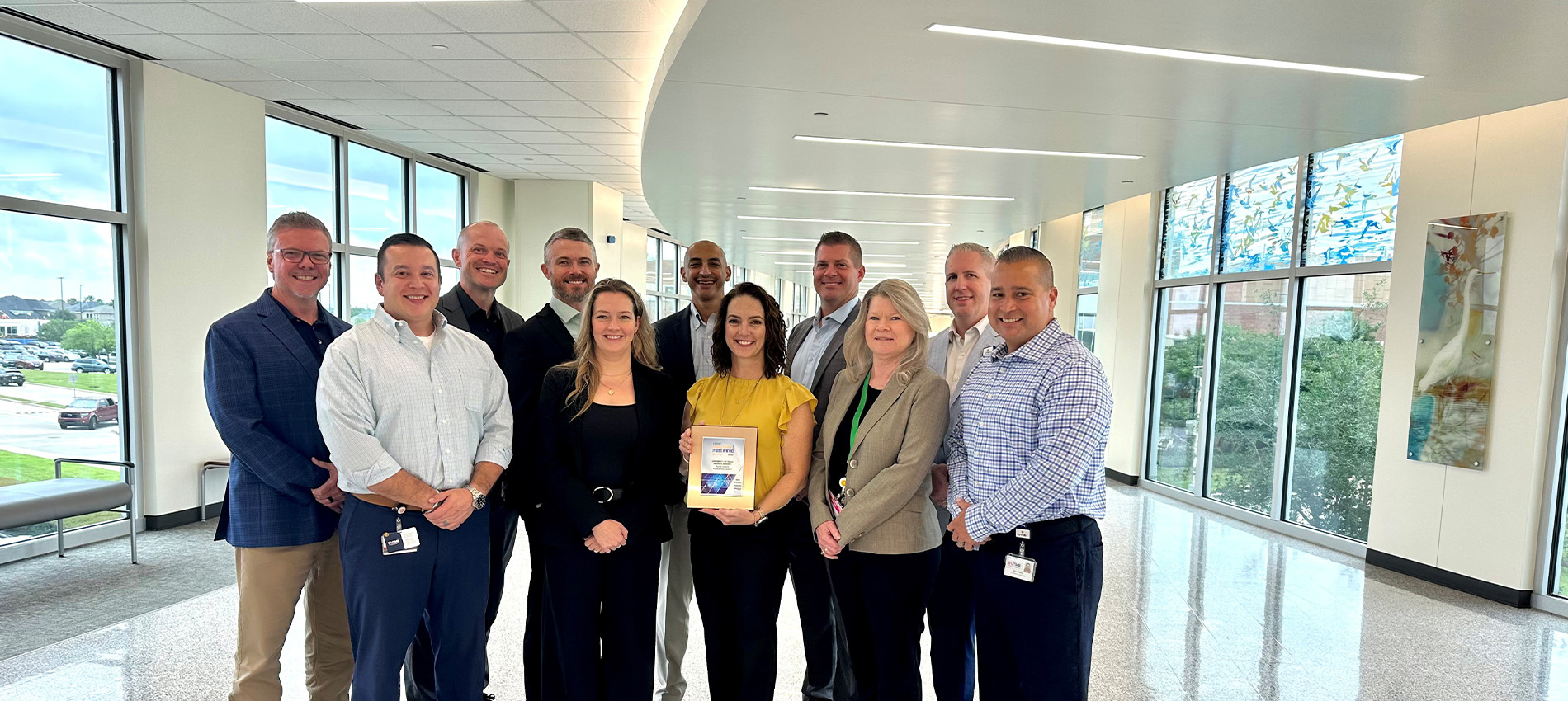 A group of 11 leaders from the UTMB Information Technology Services department stand in a group as one person holds the plaque they were awarded for being named a Most Wired healthcare institution.