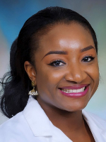  Head-and-shoulders portrait shows a woman wearing a white medical coat against a blue gradient background.  

