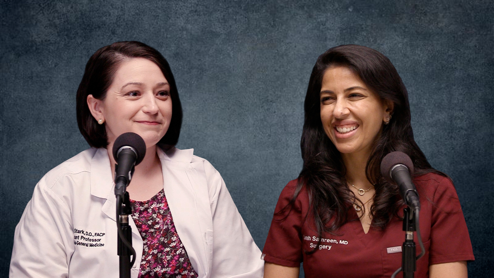 Two people seated at microphones in a podcast recording setting, one wearing a white clinical coat and the other wearing burgundy scrubs, against a blue background.