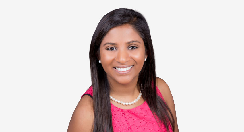 Sheba Luke appears in a pink top and pearl necklace and earrings in a professional headshot.
