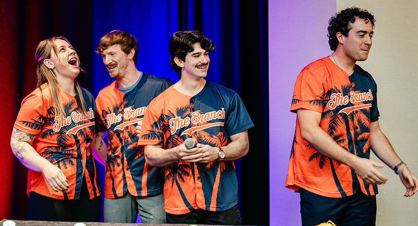 Four students wearing "The Branch" t-shirts celebrate correctly answering a trivia question.