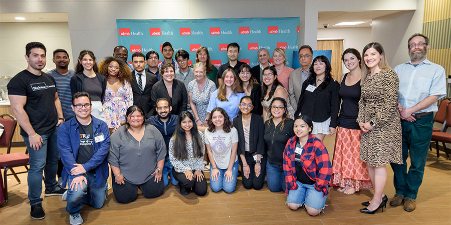 Large group of smiling students lined up in three rows, some kneeling and some standing
