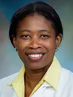 Female doctor with short brown hair wearing a white lab coat over a yellow shirt