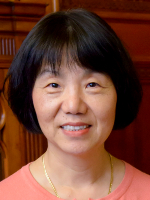 Dr. Lynn Soong Head-and-shoulders portrait of a woman with short dark hair wearing a coral top and gold necklace against a wood‑paneled background.