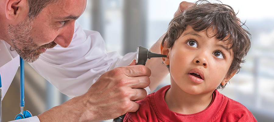 Health care provider uses an otoscope to examine a young child’s ear during a pediatric ear exam in a clinical setting